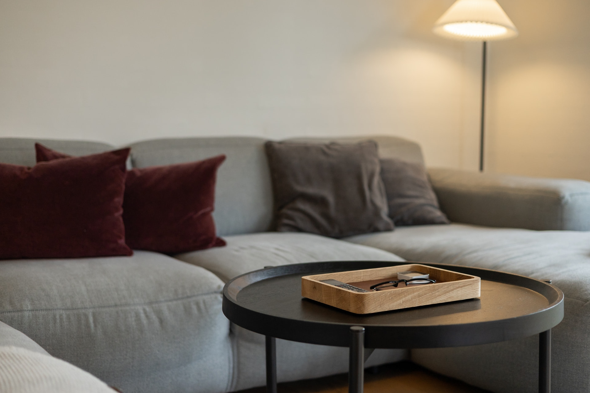 Morelund bakke i egetræ med briller på et rundt sofabord foran en sofa